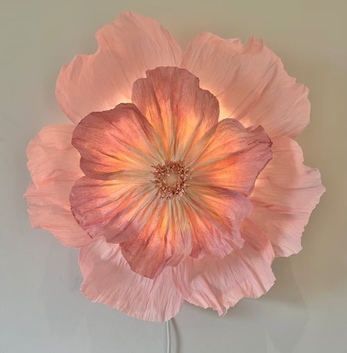 Stor væglampe formet som en lysende, lyserød blomst med flere lag blomsterblade. (1)