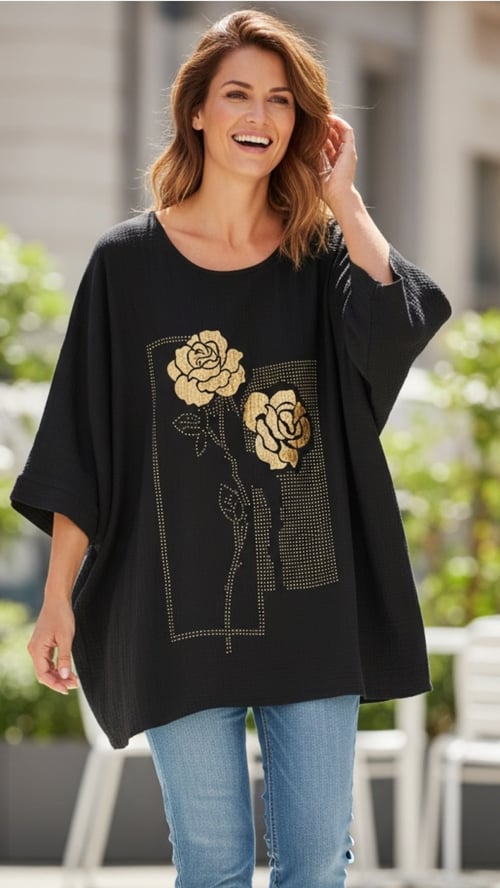 Kvinde iført sort, løstsiddende bluse med guldbelagte blomsterprint og blå jeans, smilende udendørs. (1)