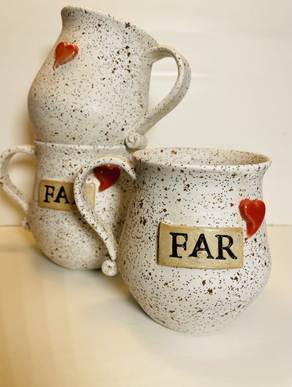Tre keramiske krus med brunlige prikker, hver med et rødt hjerte og et mærke med ordet "FAR".