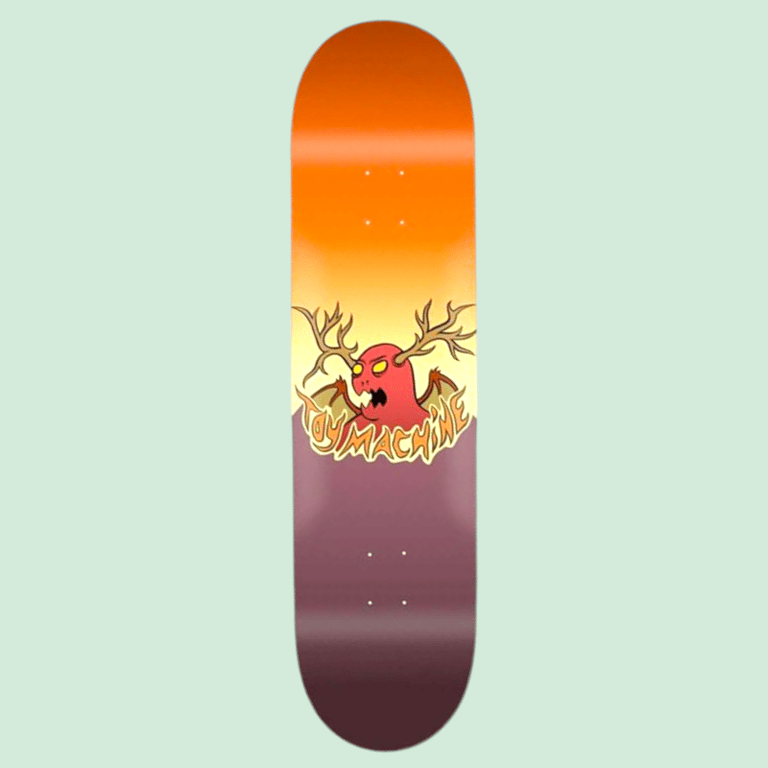 Skateboard med orange og mørk lilla gradient og en tegnet rød monstre med gevækster som horn og teksten "Toy Machine".