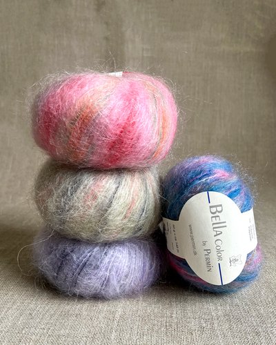 Billede af fire garnnøgler i forskellige farver med fluffy tekstur; tre stablet og en liggende med mærket "Bella Color by Permin".