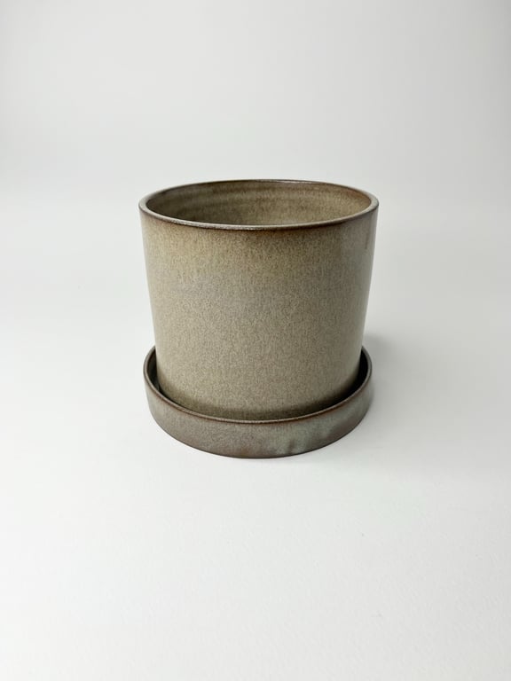 Gråt keramisk plantekrukke med underskål på hvid baggrund.