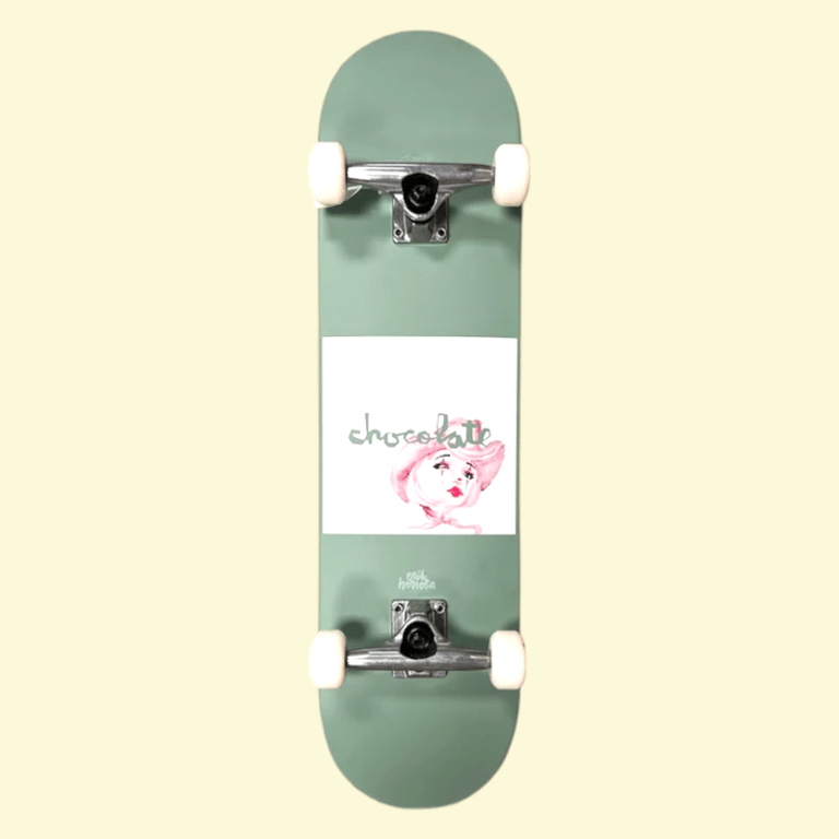 Grøn skateboard med hvidt område i midten, hvor der er en tegning af et ansigt med lyserødt hår og teksten "chocolate".