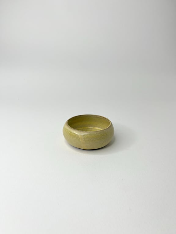 Lille rund skål i beige keramik på hvid baggrund.