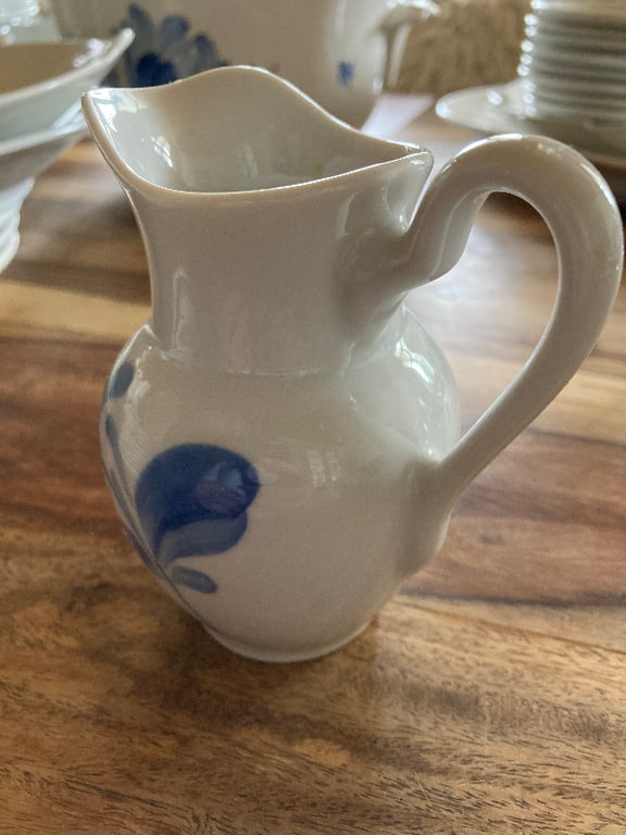Hvid keramisk kande med hank og blå blomstermotiv, placeret på et træbord. (4)