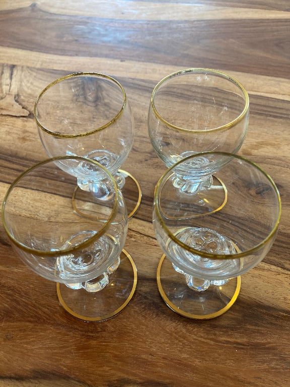Fire små glas med guldkant placeret på et træbord set ovenfra. (3)