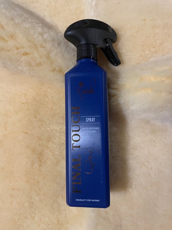 Flaske med blå spraybottle mærket "Final Touch Spray" placeret på lyst tæppe.