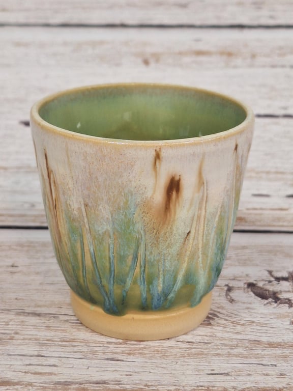 Keramikkrus med grønlig and brun glasur og mønster, placeret på lyst træbord.