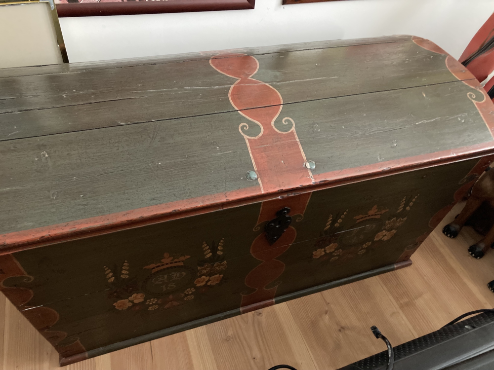 Gammel malet trækiste med røde og grønne dekorative mønstre placeret på trægulv. (2)