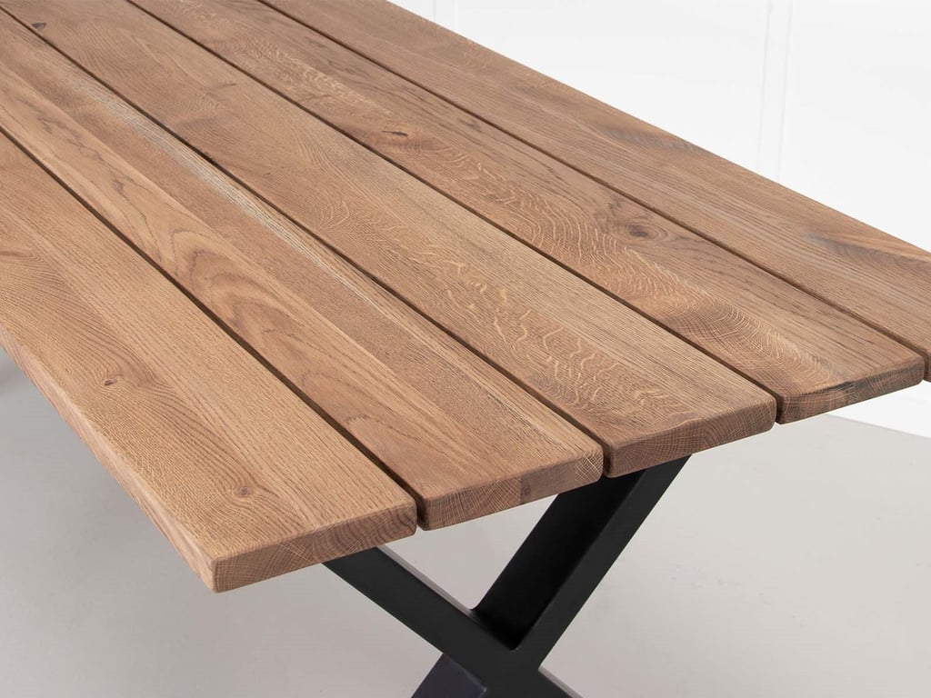 Tæt billede af bordplade lavet af træplanker med sort metalstel.