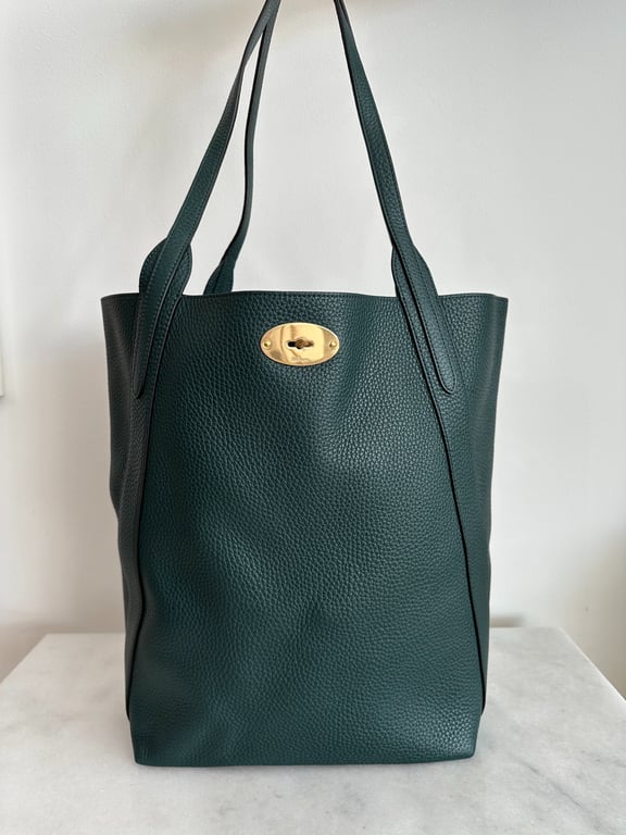 Grøn textured lædertaske med to skulderstropper og guldfarvet oval lås, placeret på hvid baggrund.