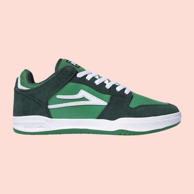 Grøn og mørkegrøn sneaker med hvide snørebånd og hvid sål på lyserød baggrund.