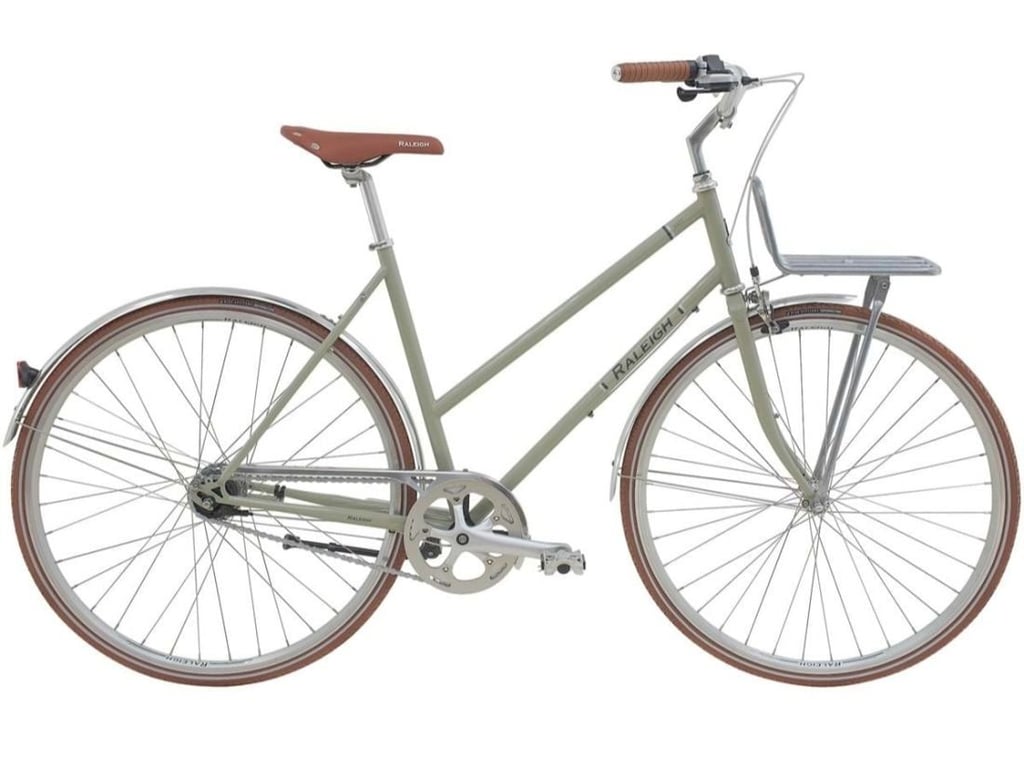 Billede af en klassisk herrecykel i lysegrøn med brunt sadel og håndtag, udstyret med metal bagagebærer foran og skærme på begge hjul.