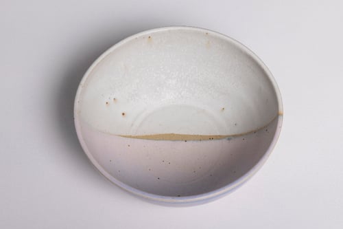 Keramisk skål med glaseret hvid og lyserød overflade samt små brune pletter.