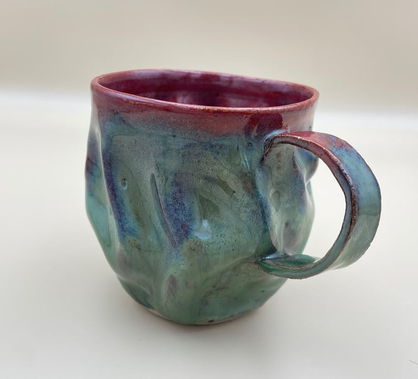 Keramikkrus med bølget overflade og glasur i grønne, blå og røde nuancer.