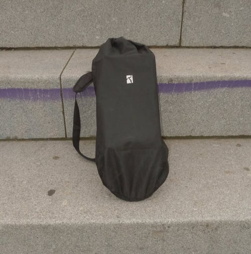 Sort opbevaringspose med skulderrem, placeret på en betontrappe med en lilla streg bagved. (1)