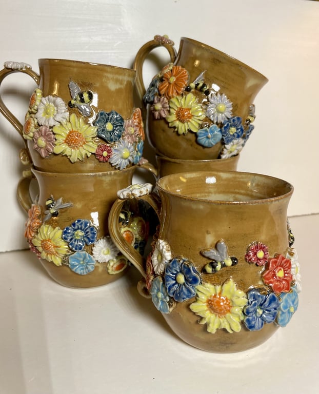 Fire brune keramikkrus med farverige, detaljerede blomster og bier som dekorationer.