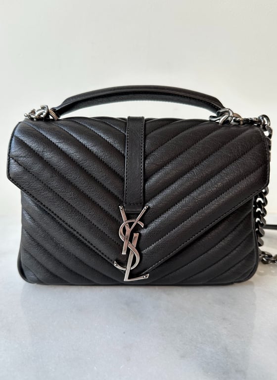 Sort quiltet skuldertaske i læder med metallogo og kæde.