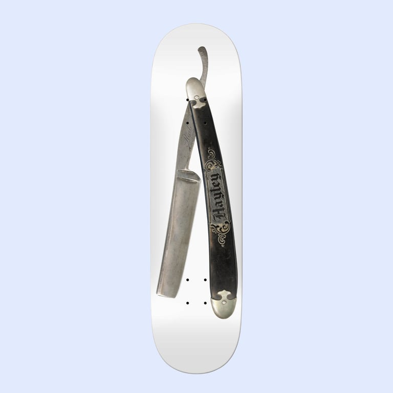 Skateboard deck med billede af en åben barberkniv på en hvid baggrund.