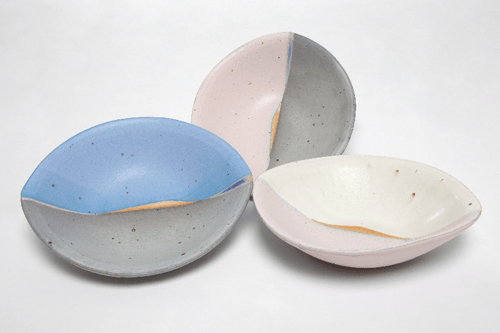 Tre farvede, knuste skåle i pastelnuancer står på en hvid baggrund.
