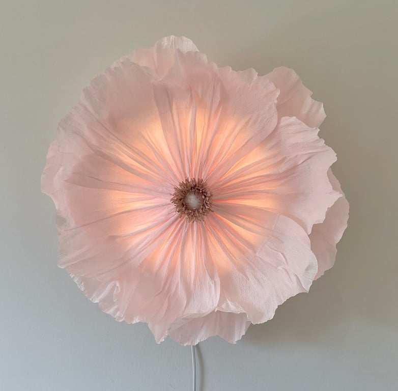 Blomstformet væglampe med bløde, lyserøde skygger og lyskilde i midten.