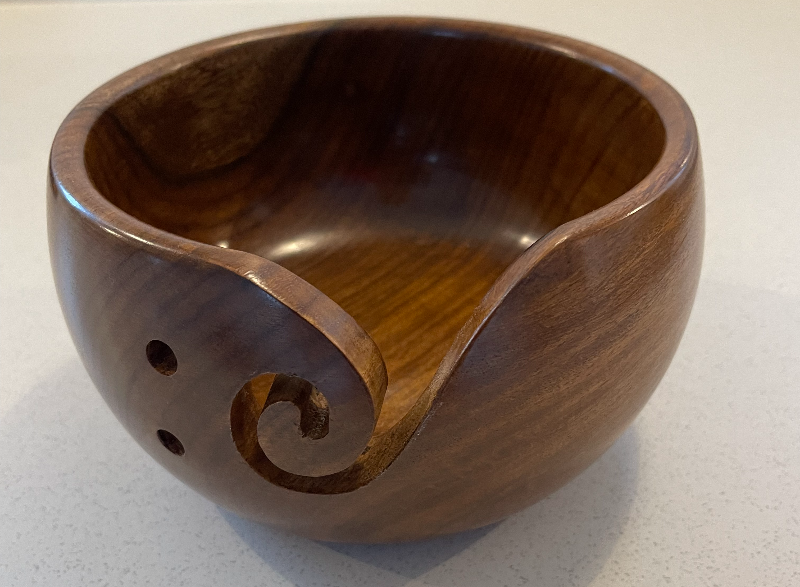 Træskål med en snoet udskæring og to huller, designet til at holde garn under strikning.