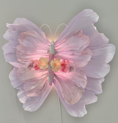 En dekorativ sommerfugl lavet af lyserøde blomsterblade og kunstige blomster med en blød lysende effekt. (1)