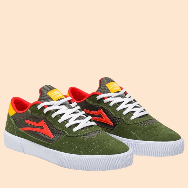 Par af grønne sneakers med hvide snørebånd, røde og gule detaljer samt hvide såler på beige baggrund.