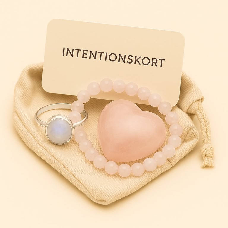 Billede af en stofpose med en sølvring med en hvid sten, et armbånd af lyserøde perler, en lyserød hjerteformet sten og et kort med teksten "INTENTIONSKORT". (2)