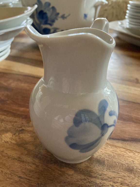 Hvid porcelænsflødekande med blå blomstermotiv på en træbordplade. (3)