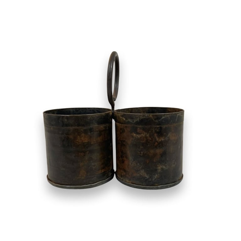 Rustik metalbeholder med to sammenhæftede cylindriske rum og et håndtag i midten.
