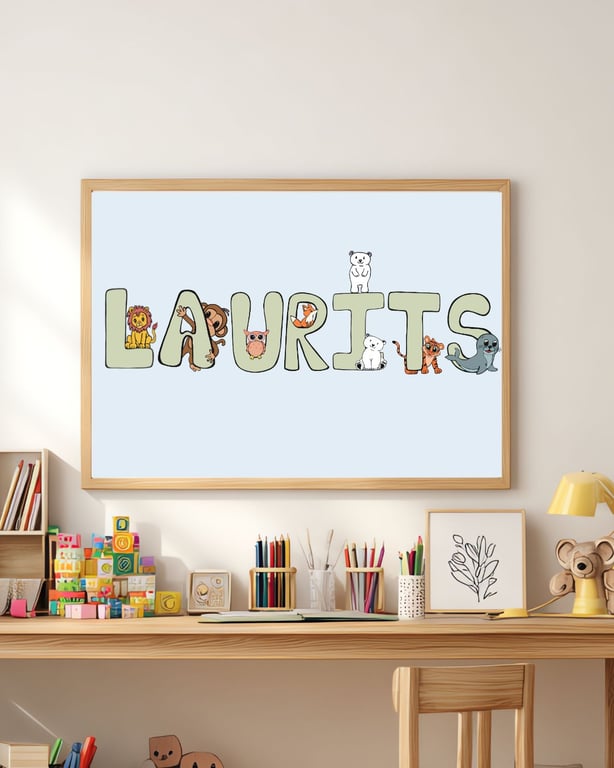 Plakat med navnet "Laurits" i store bogstaver med små tegneserie-dyr placeret på og omkring bogstaverne, hængende over et børnearbejdsbord med farveblyanter, byggeklodser og børnekunst.