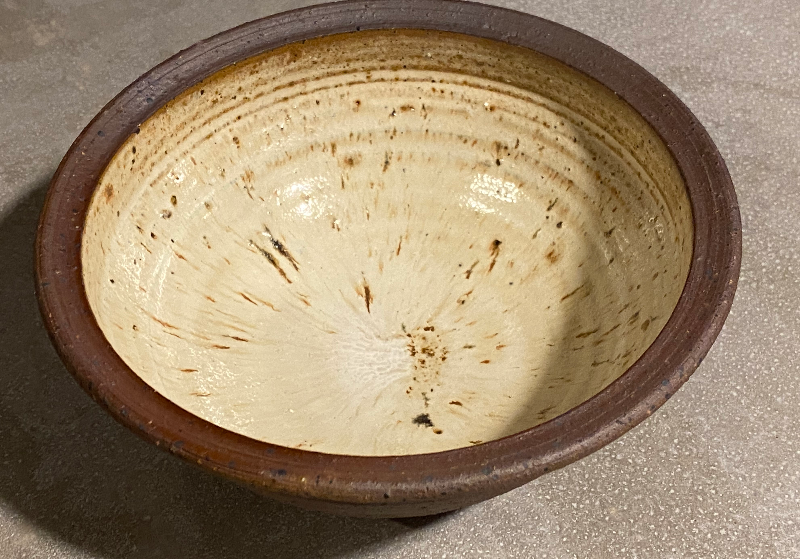 Skål i beige glasur og mørkstentøjsler. Den er brændt reducerende med træ.