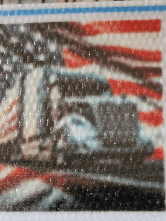 Nærbillede af et frimærke med et lastbilmotiv foran et amerikansk flag.