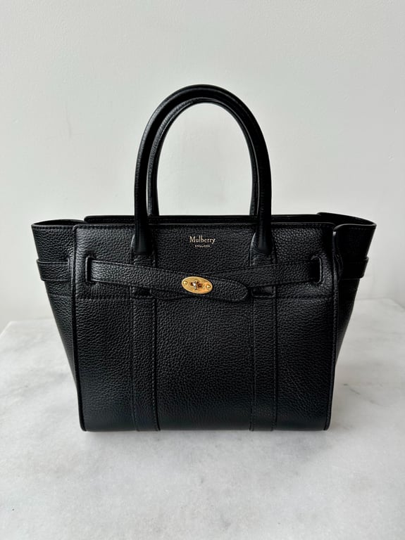 Sort Mulberry håndtaske i tekstureret læder med to håndtag og guld spænde, placeret på hvid marmorbord.