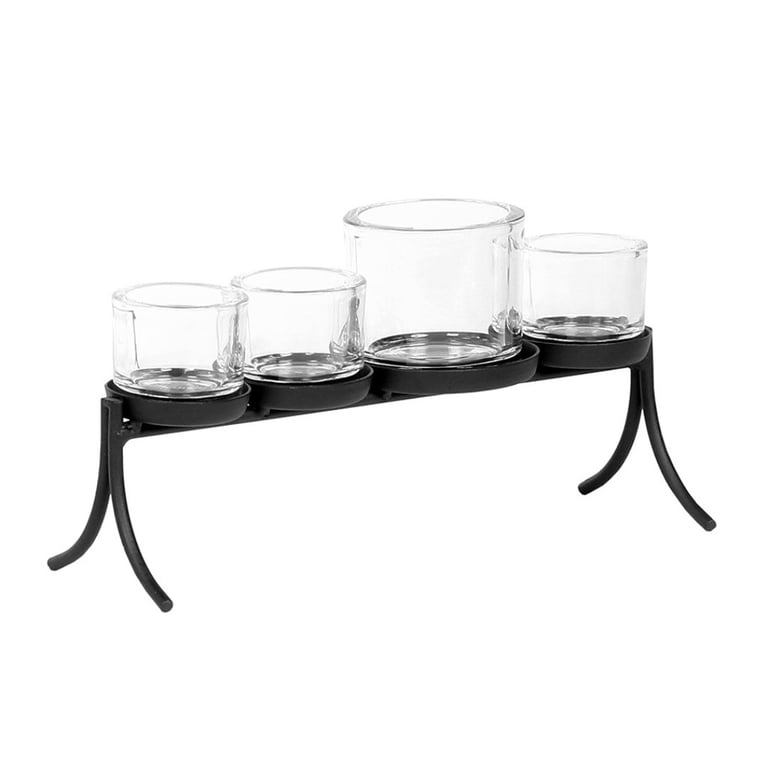 Fire glaslysestager i forskellig størrelse placeret i en sort metalramme med ben.