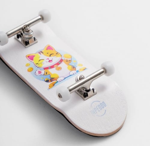 Hvid fingerboard med en tegning af en lykkelig kat omgivet af guldmønter på overfladen. (1)