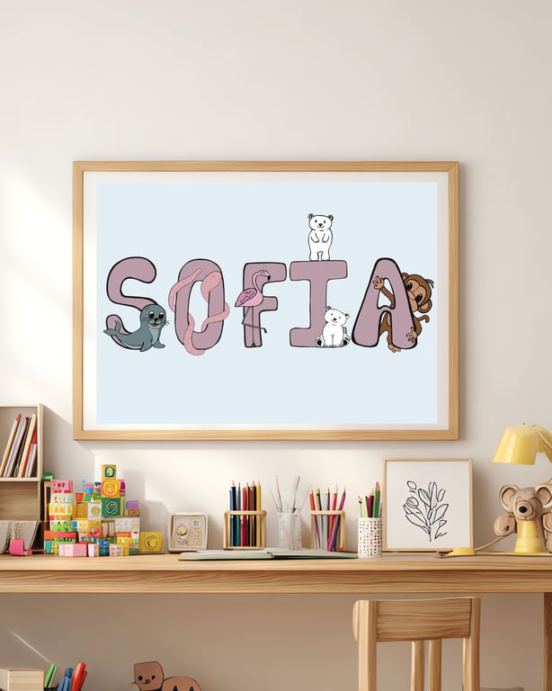 Børneværelse med skrivebord, farveblyanter og stablede klodser, over hvilket en indrammet plakat med navnet "SOFIA" hænger, hvor bogstaverne er pyntet med tegninger af forskellige dyr.
