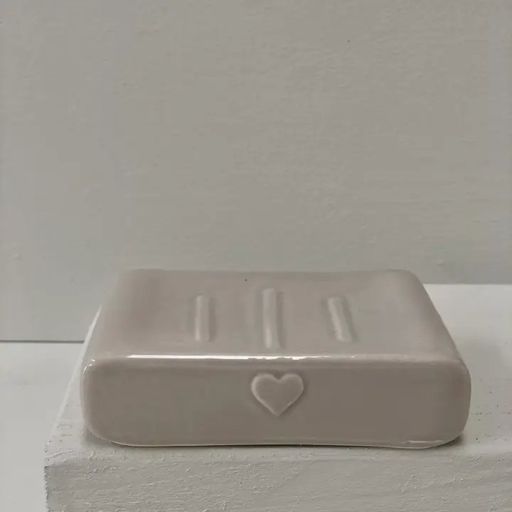 Hvidt, rektangulært sæbeskål i keramik med hjerteformet motiv på fronten, placeret på en hvid overflade. (2)