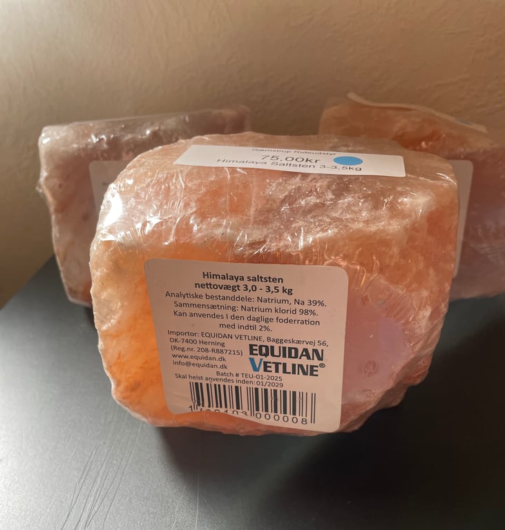 Himalaya saltsten indpakket i plast med tekstetiket fra producenten Equidan Vetline, placeret på en grå overflade.
